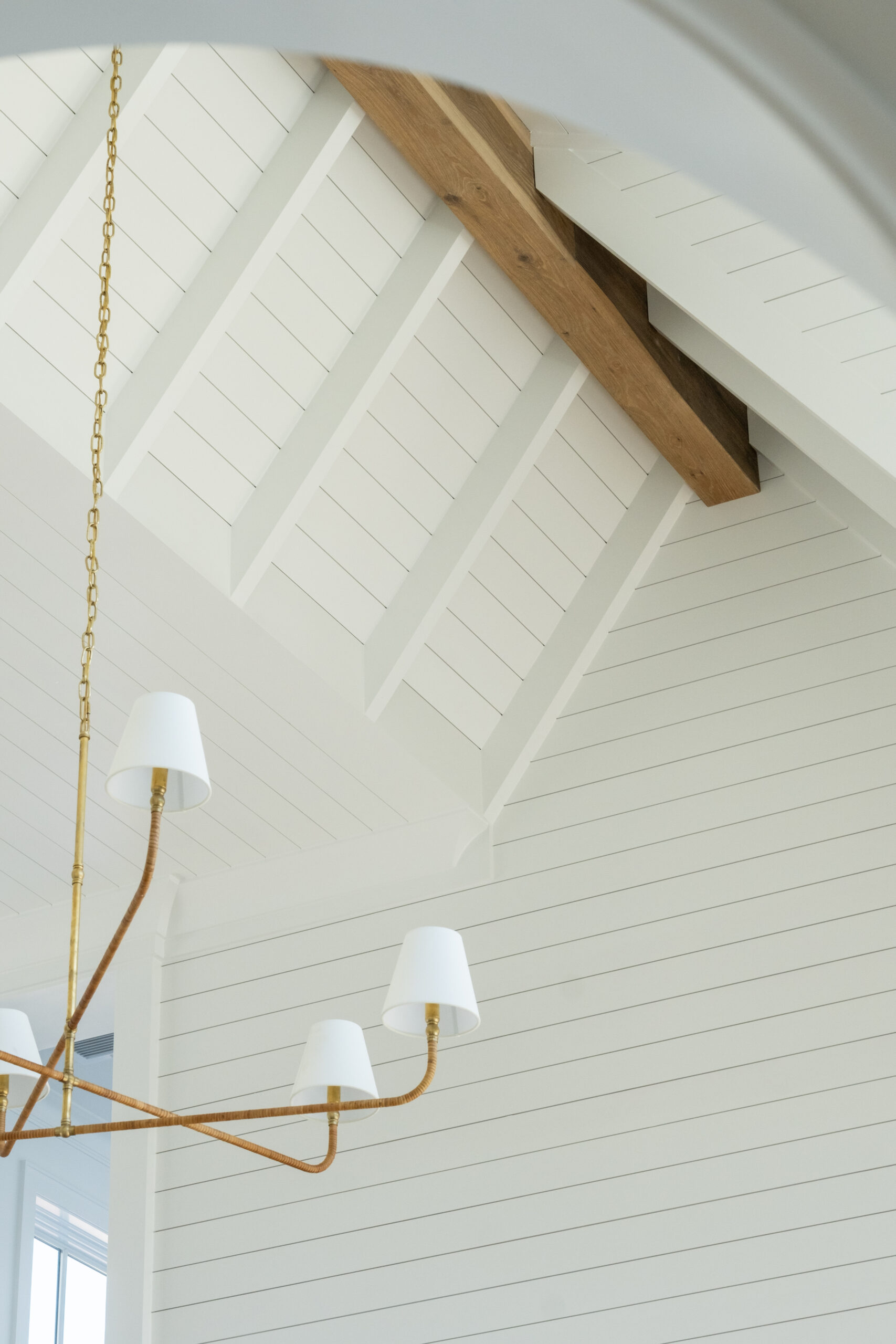 vaulted ceilings with exposed beams and chandelier